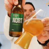 Jonathan holding Nort Refreshing Ale bottle in one hand and glass with beer in the other