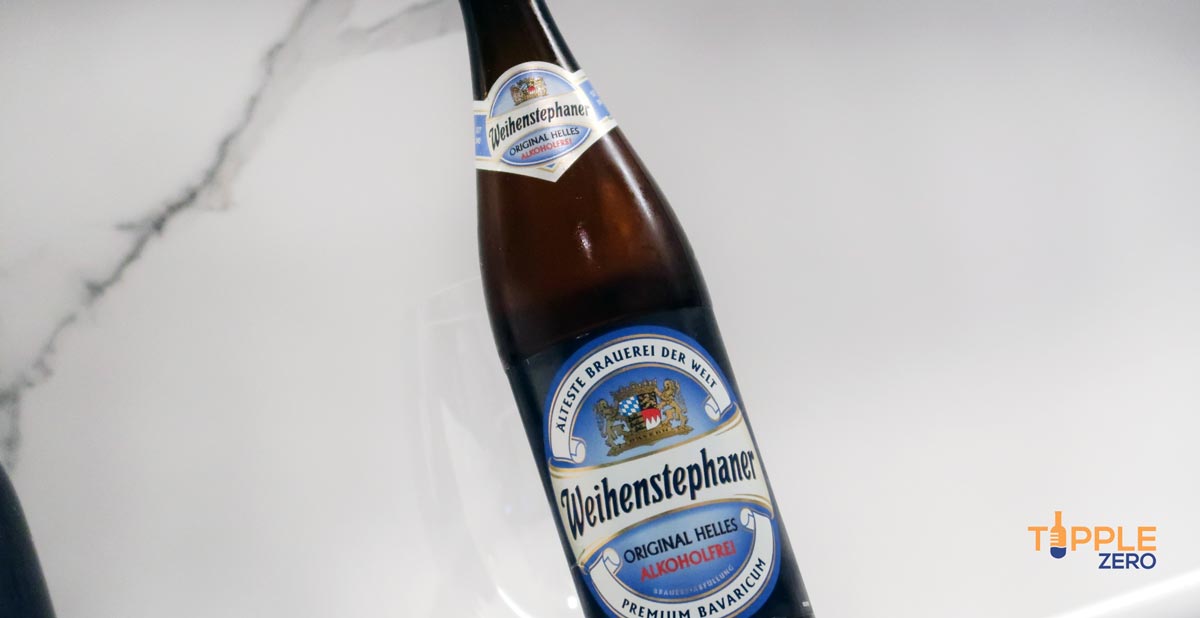 Weihenstephaner Alcohol Free Helles Lager bottle on angle in front of spiegelau glass