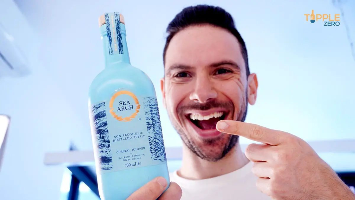 Man holding non-alcoholic gin made by sea arch and smiling